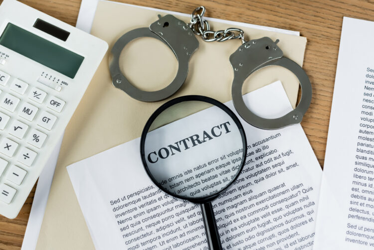 top view of magnifier on papers with contract lettering near calculator and handcuffs
